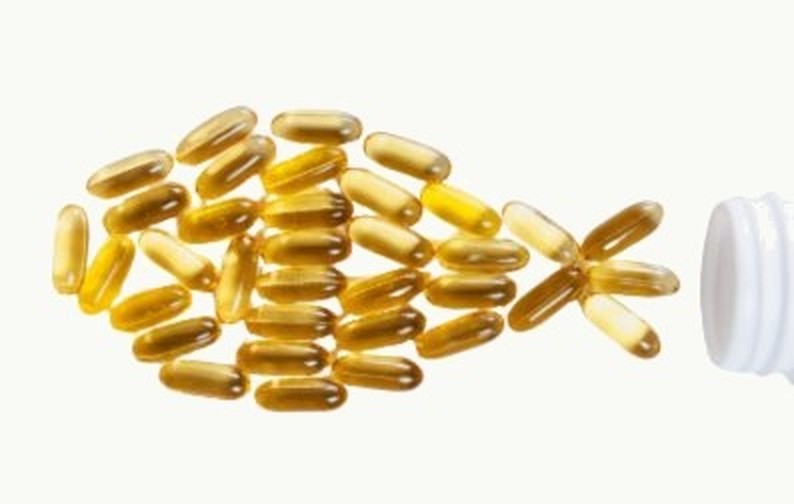 Omega-3 capsules arranged in the shape of a fish, spilling from a bottle